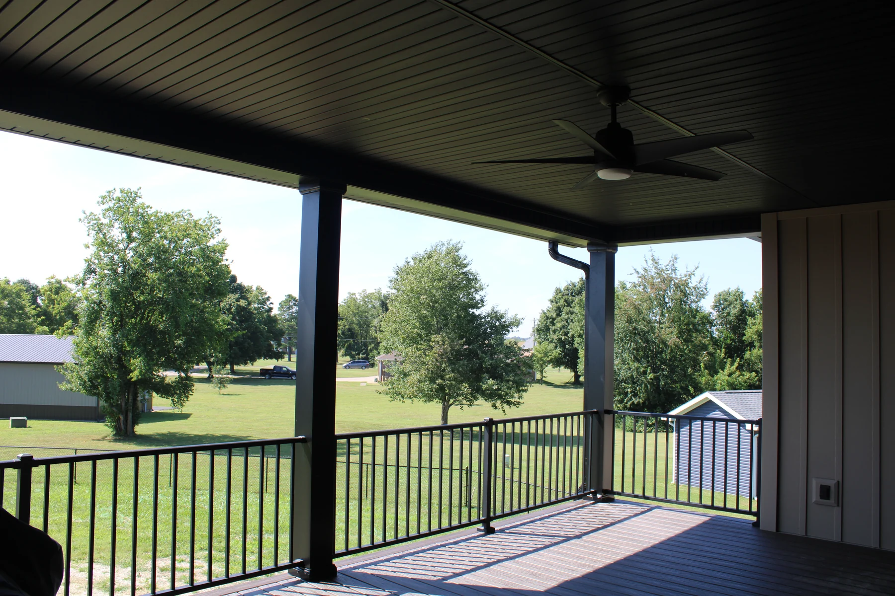 A covered deck with dark railing creates a comfortable place to spend time outside.