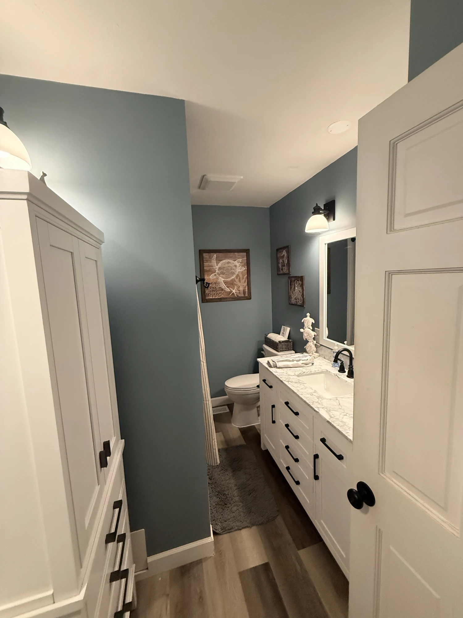 Finished blue bathroom with white vanity, marble-look countertop and black fixtures at a Shorehome Kentucky project.