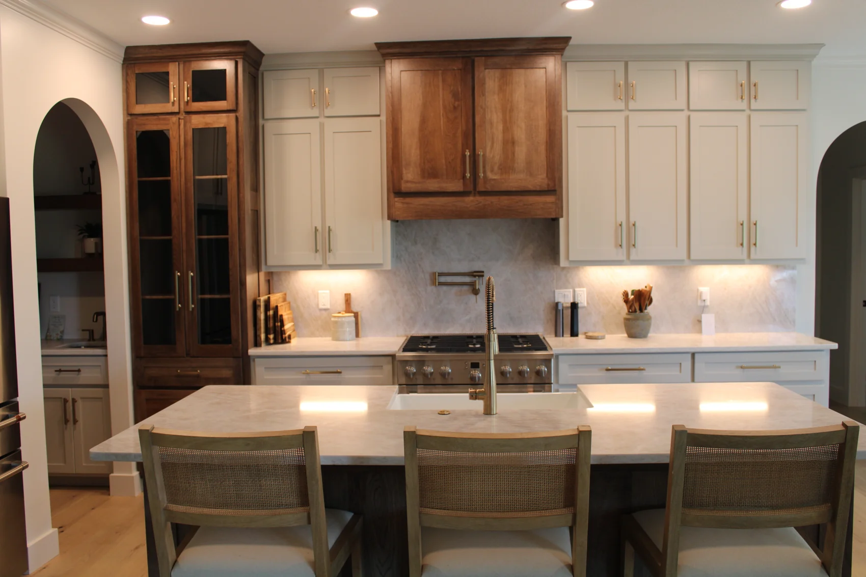 A second view of the kitchen shows the warm wood cabinetry and lighting around the gathering island.